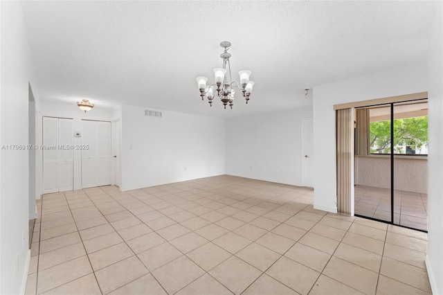 spare room featuring an inviting chandelier, light tile patterned flooring, and visible vents