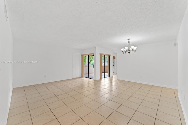 empty room with baseboards, a notable chandelier, light tile patterned floors, and a textured ceiling