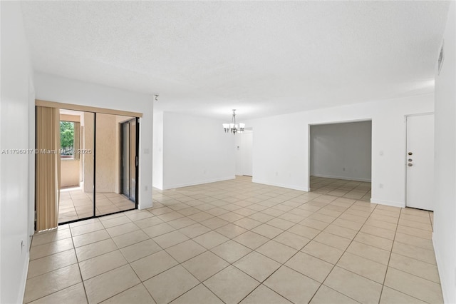 spare room with light tile patterned floors, a chandelier, baseboards, and a textured ceiling