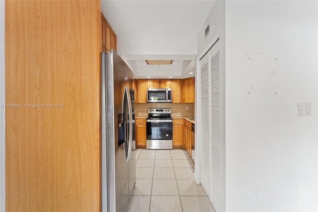 kitchen with light tile patterned floors, visible vents, backsplash, a raised ceiling, and appliances with stainless steel finishes