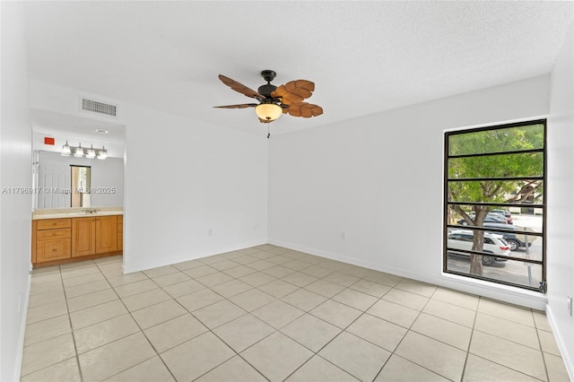 spare room featuring light tile patterned floors, visible vents, and a ceiling fan