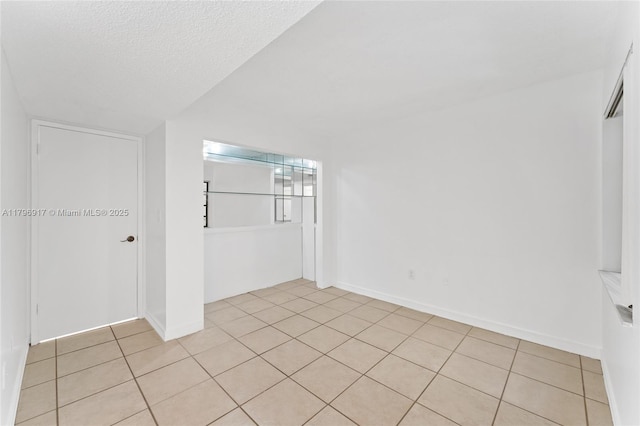 empty room featuring baseboards and light tile patterned flooring