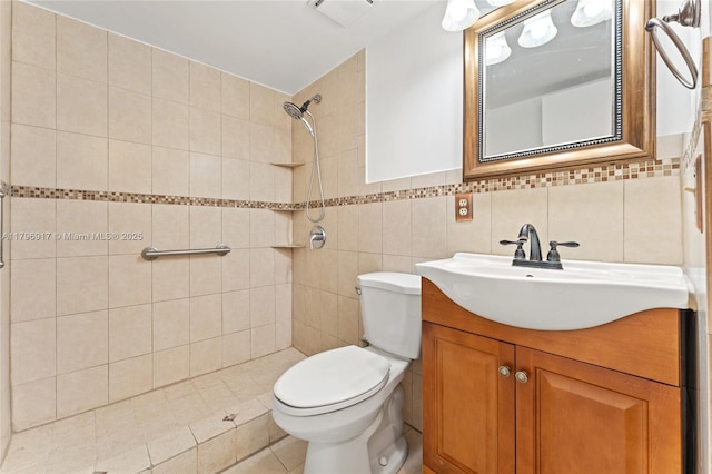 full bathroom with toilet, tiled shower, tile walls, tile patterned flooring, and vanity