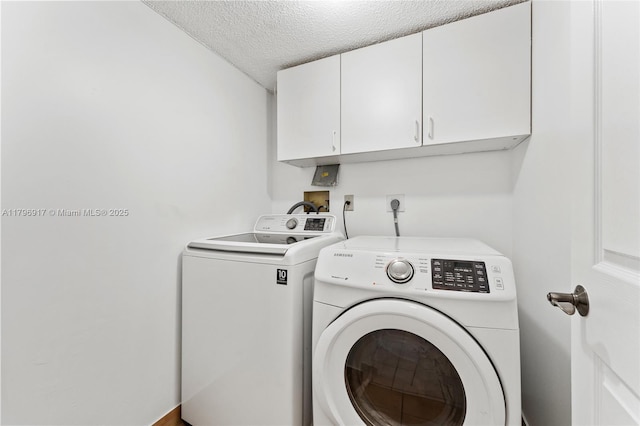 clothes washing area with cabinet space, a textured ceiling, and washer and dryer