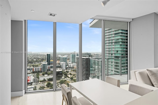 dining room featuring a city view, floor to ceiling windows, visible vents, and a healthy amount of sunlight