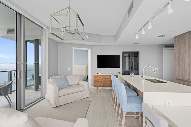 living area featuring a chandelier, floor to ceiling windows, track lighting, and visible vents