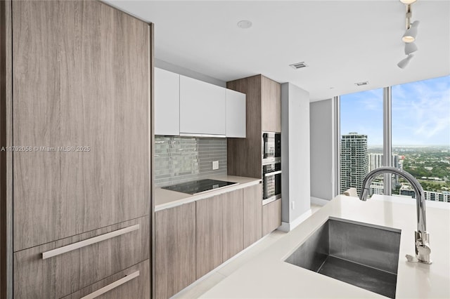 kitchen featuring a sink, visible vents, decorative backsplash, modern cabinets, and appliances with stainless steel finishes