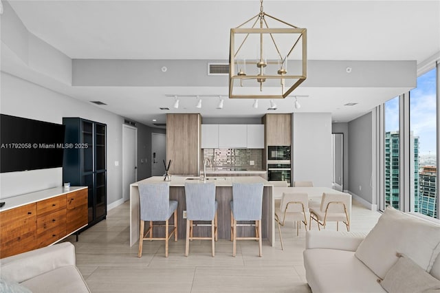 kitchen featuring a kitchen breakfast bar, decorative backsplash, open floor plan, light countertops, and modern cabinets