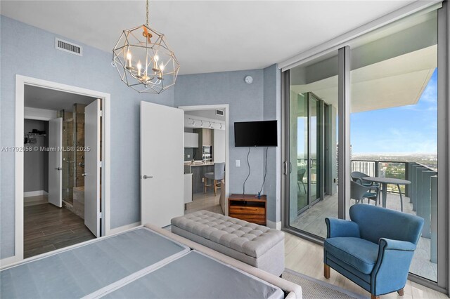 bedroom featuring an inviting chandelier, visible vents, wood finished floors, and baseboards