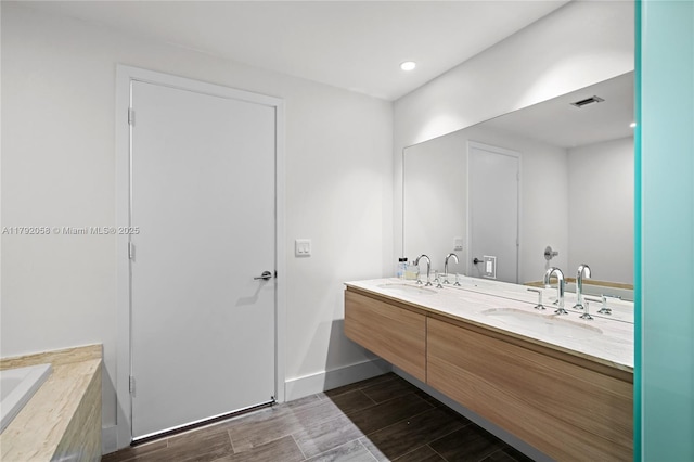 full bathroom featuring double vanity, visible vents, wood finish floors, and a sink
