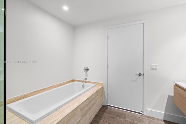 bathroom featuring a garden tub, vanity, recessed lighting, and wood finished floors