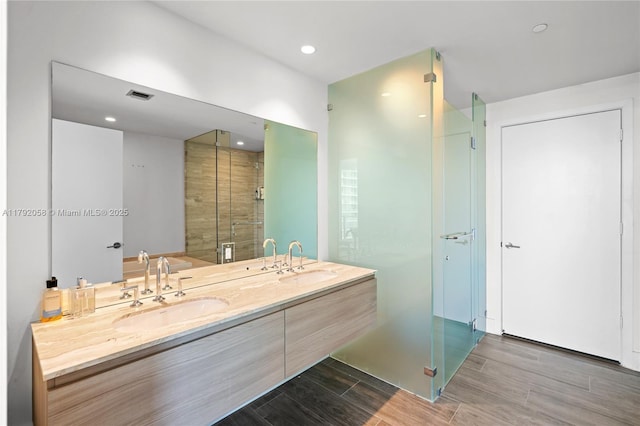 bathroom featuring a sink, double vanity, wood tiled floor, and visible vents