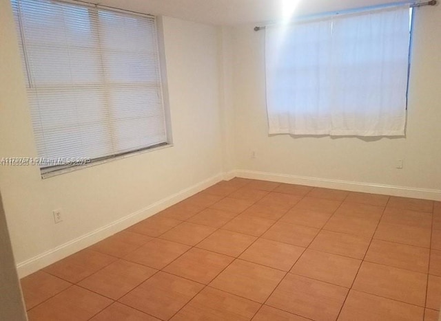 empty room with light tile patterned floors and baseboards