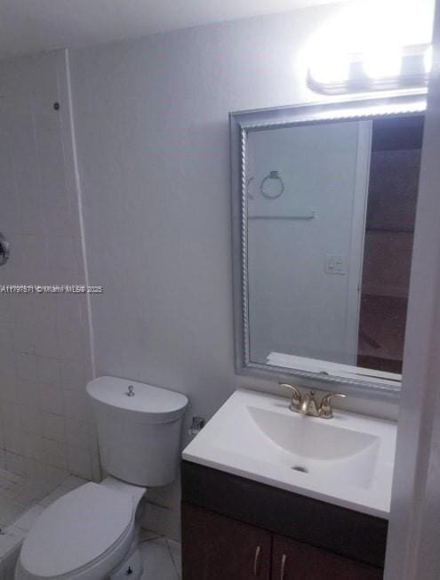 full bathroom with vanity, toilet, and tiled shower