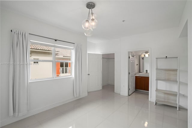 18445 NE 27th Pl, Aventura, FL 33160 - unfurnished bedroom with baseboards, light tile patterned floors, a sink, connected bathroom, and a walk in closet