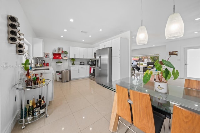 kitchen featuring a sink, recessed lighting, white cabinetry, hanging light fixtures, and appliances with stainless steel finishes
