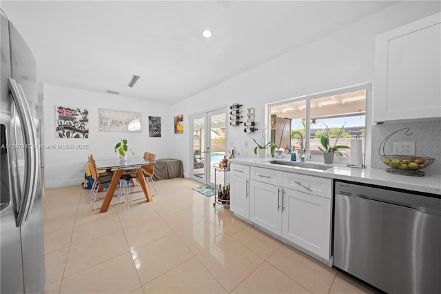 kitchen with french doors, a sink, stainless steel appliances, white cabinetry, and light countertops