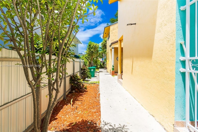 view of side of home with stucco siding and fence