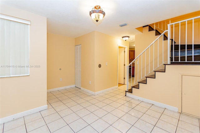 unfurnished room with visible vents, baseboards, and stairway