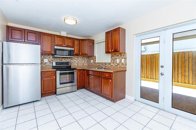 kitchen featuring a sink, stainless steel appliances, tasteful backsplash, light countertops, and light tile patterned floors
