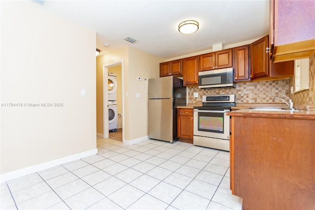 kitchen with stacked washer and dryer, a sink, visible vents, appliances with stainless steel finishes, and tasteful backsplash