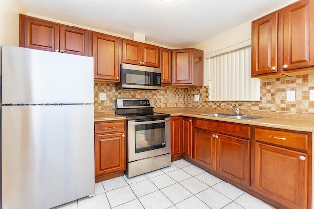 kitchen featuring light tile patterned floors, a sink, decorative backsplash, light countertops, and appliances with stainless steel finishes