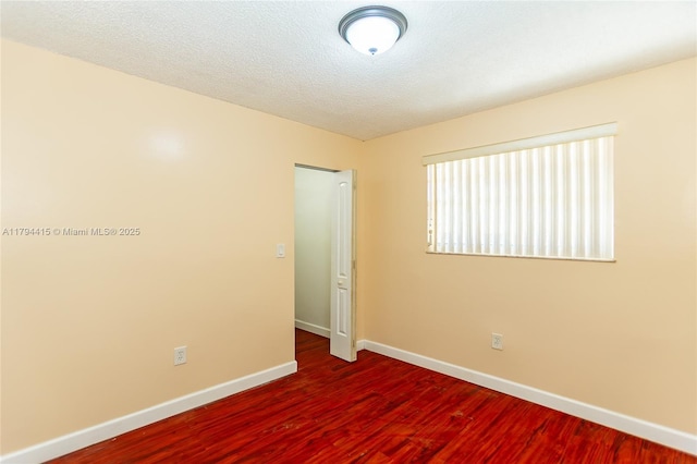 spare room featuring baseboards and wood finished floors