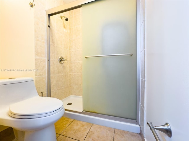 bathroom with tile patterned floors, toilet, and a shower stall