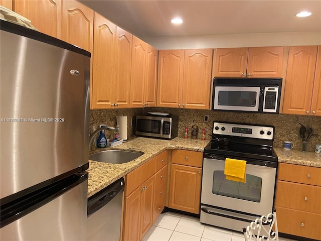 kitchen featuring light stone countertops, light tile patterned floors, a sink, stainless steel appliances, and tasteful backsplash