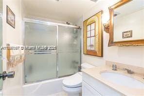 bathroom featuring toilet, vanity, and enclosed tub / shower combo