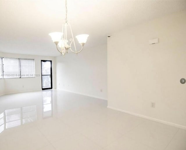 20850 San Simeon Way Unit 408-5, Miami, FL 33179 - empty room featuring light tile patterned floors, baseboards, and a chandelier