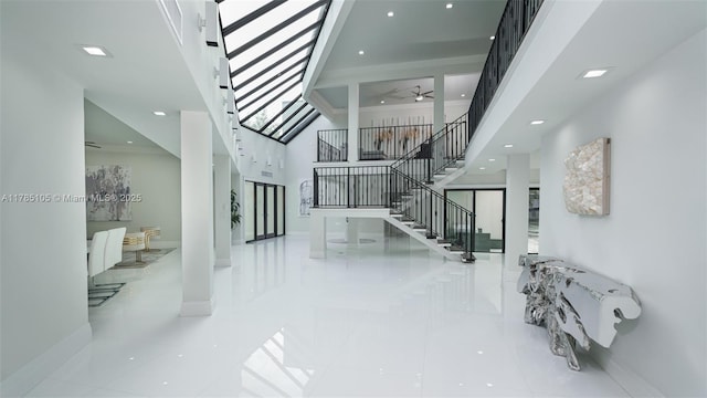 entryway with ceiling fan, stairway, baseboards, and a high ceiling