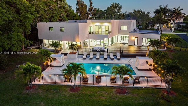 back of house featuring a patio area, fence, a community pool, a balcony, and stucco siding