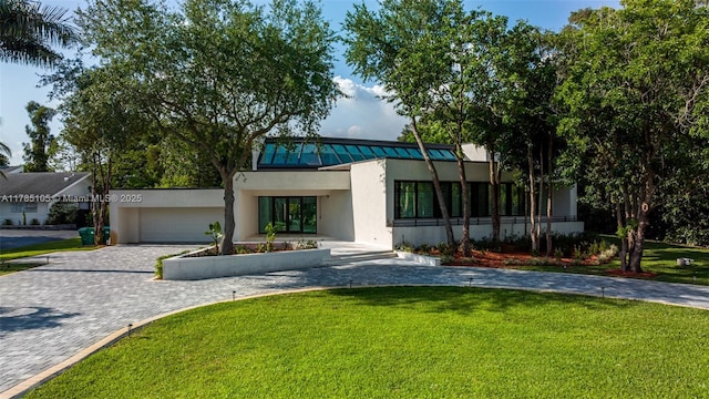 view of front of home featuring stucco siding, a front lawn, a garage, and decorative driveway