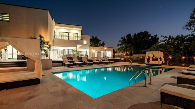 pool at twilight featuring a patio area, fence, and a fenced in pool