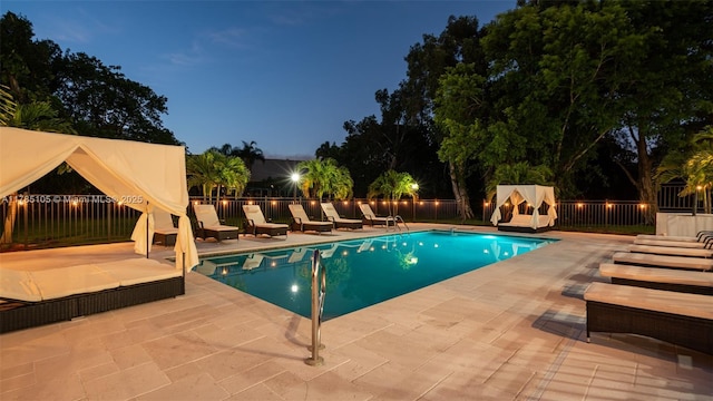 pool at twilight with a patio area, a fenced backyard, and a fenced in pool