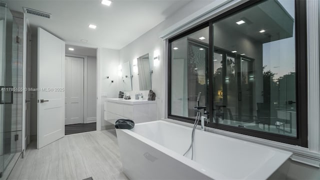 full bath with a freestanding tub, vanity, and visible vents