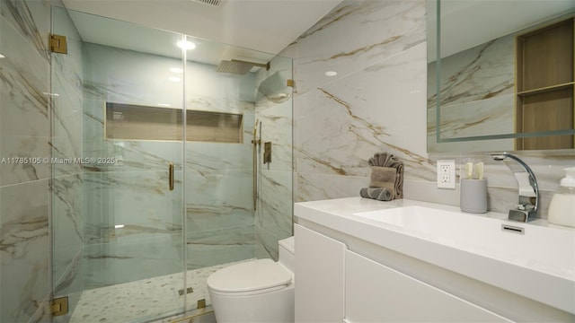 bathroom with a marble finish shower, tile walls, vanity, and toilet