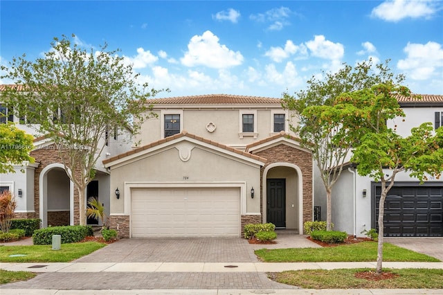 mediterranean / spanish home featuring stone siding, stucco siding, and decorative driveway