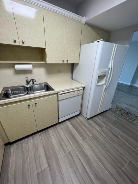 kitchen with white appliances, light countertops, a sink, and light wood-style floors