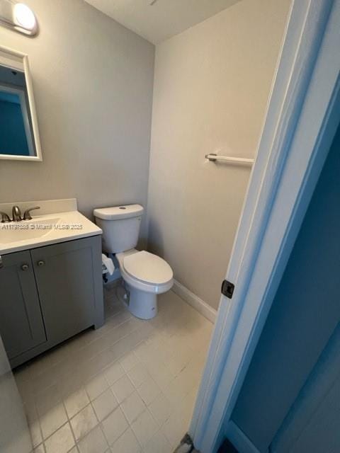 half bath with tile patterned floors, toilet, and vanity