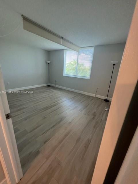 empty room with baseboards and wood finished floors