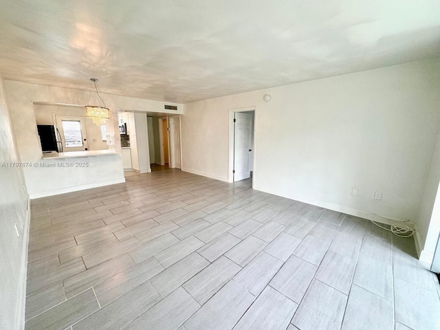 unfurnished living room with visible vents, baseboards, and wood tiled floor