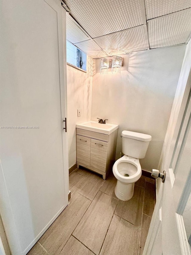 bathroom with vanity, toilet, wood tiled floor, and baseboards