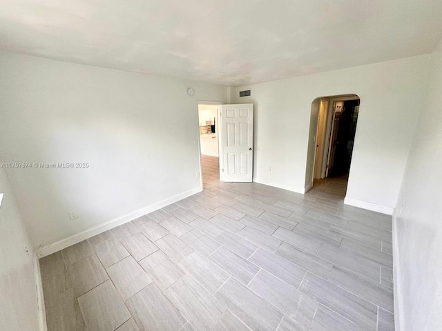 unfurnished room with arched walkways, baseboards, and visible vents