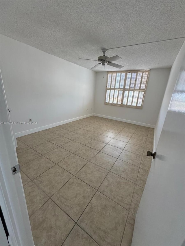 tiled empty room featuring a textured ceiling, baseboards, and ceiling fan