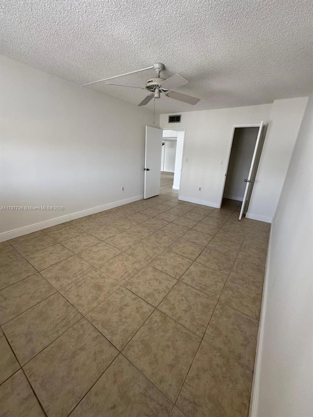 unfurnished bedroom with tile patterned floors, a textured ceiling, visible vents, and baseboards