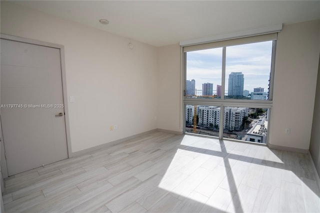 1010 SW 2nd Ave Unit 1703, Miami, FL 33130 - unfurnished room featuring baseboards, light wood finished floors, a view of city, and floor to ceiling windows