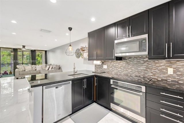 kitchen with backsplash, stainless steel appliances, a peninsula, and a sink