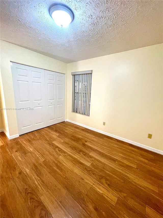 5400 NW Emblem St, Port St Lucie, FL 34983 - unfurnished bedroom featuring wood finished floors, baseboards, a closet, and a textured ceiling